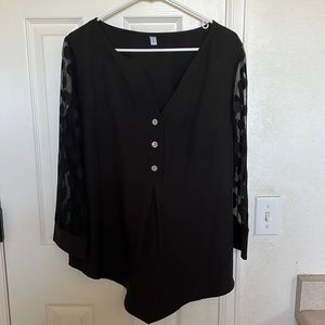Black v-neck blouse with polka-dot sheer lace sleeves.